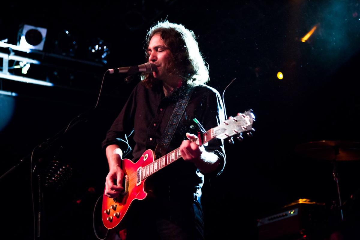 Performer singing and playing red electric guitar at the Powerstation, Auckland